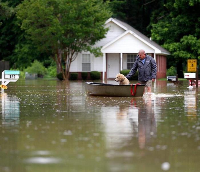 man and his dog in flood waters
